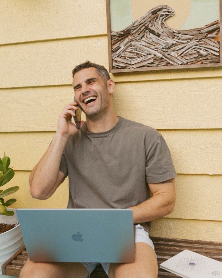 Andreas laughing on a phone call, laptop open on his lap